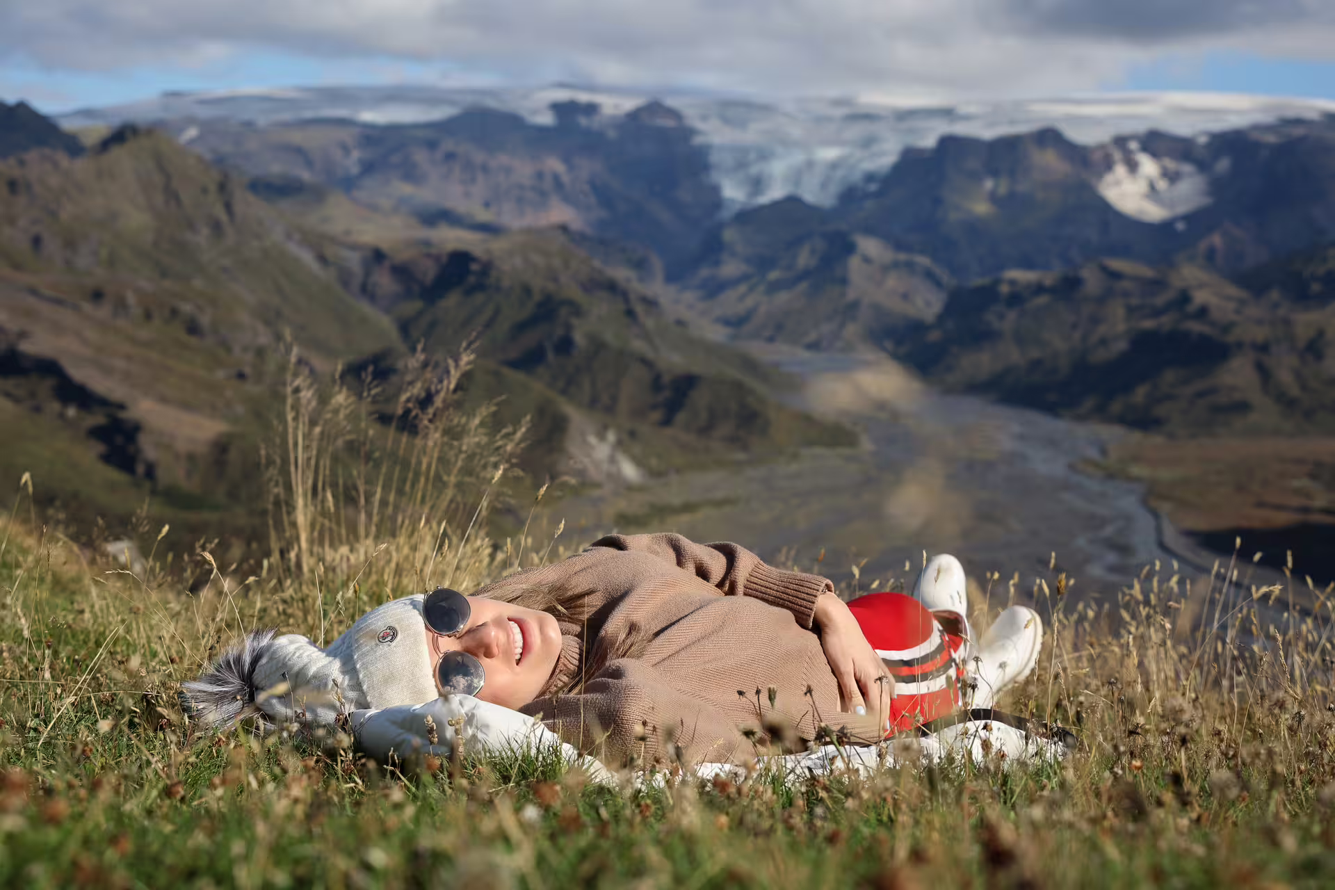 Traveler relaxing on grassy Thorsmork highland with stunning glacier valley views on Iceland full-day 4x4 tour