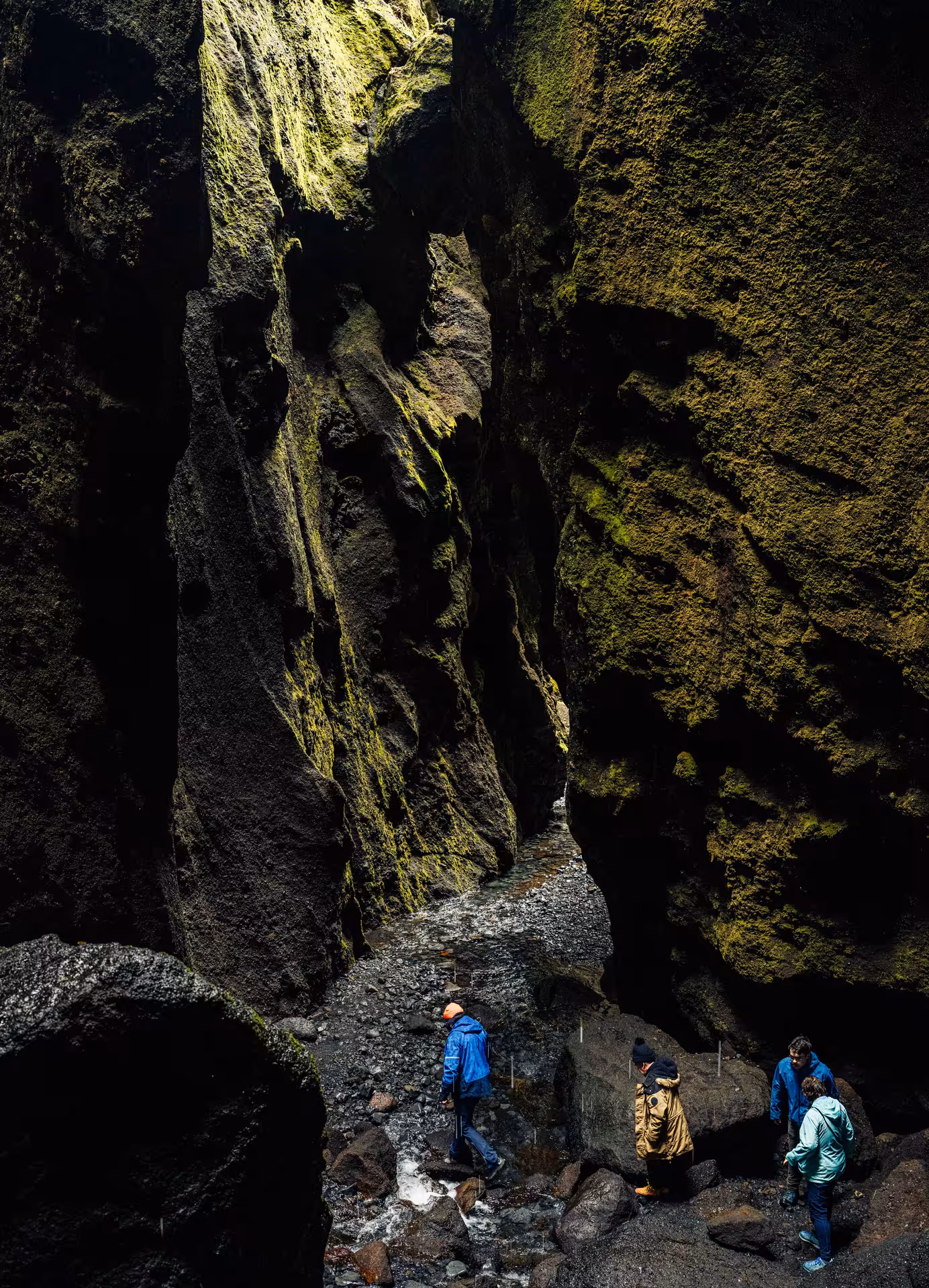 Hikers exploring narrow moss-covered canyon walls in Thorsmork, Iceland