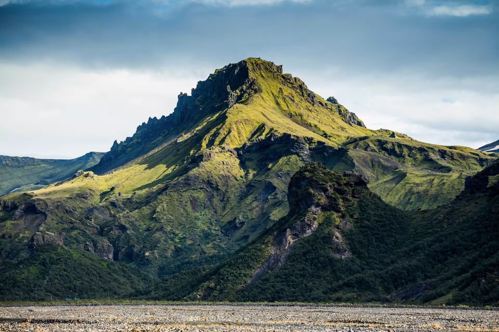 Lush green volcanic mountain peak in Thorsmork Iceland under dramatic cloudy sky