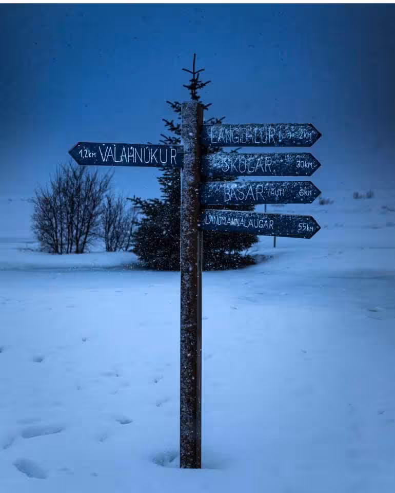 Snowy directional signpost pointing to Thorsmork trails including Landmannalaugar and Skogar in Iceland winter