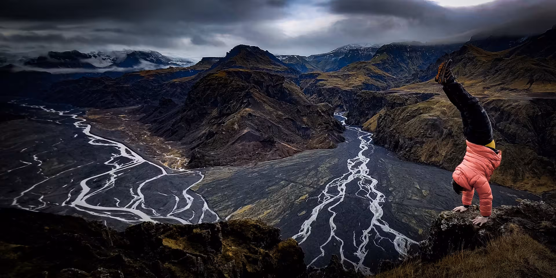 Person doing handstand on cliff overlooking Thorsmork Valley braided glacial rivers Iceland