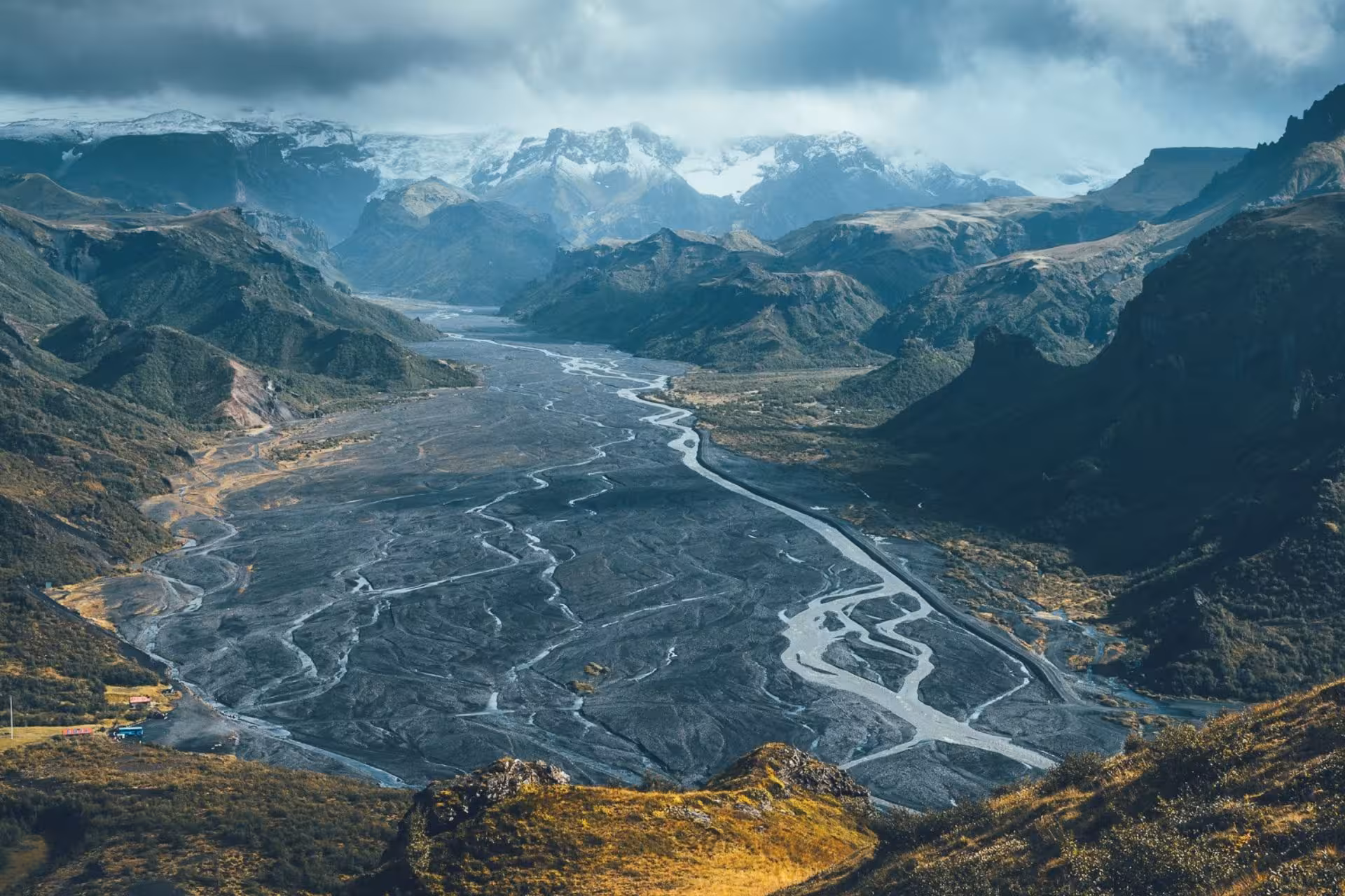 Aerial view of Thorsmork valley with braided glacial rivers, green mountains, and snow-capped peaks in Iceland