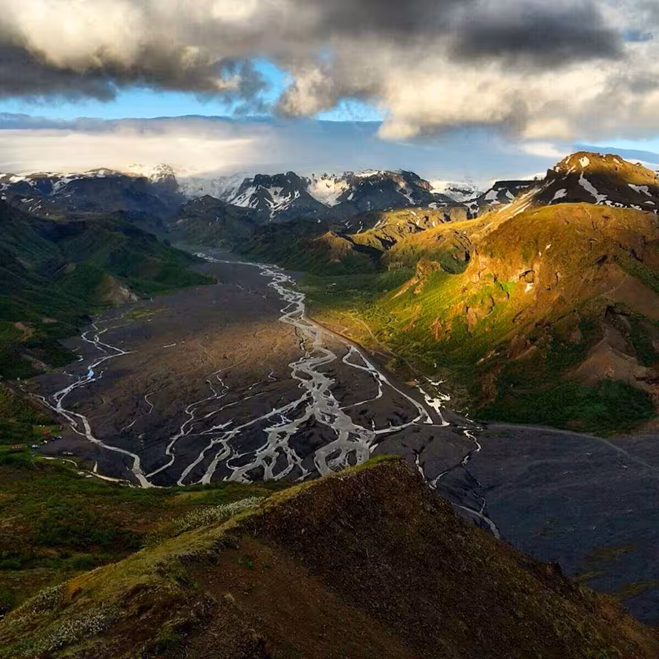 Aerial view of Thorsmork valley with braided glacial rivers, green mountains, and snow-capped peaks in Iceland