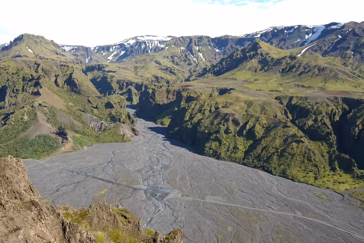 Aerial view of Thorsmork valley with braided glacial river, green mountains and snow-capped peaks in Iceland