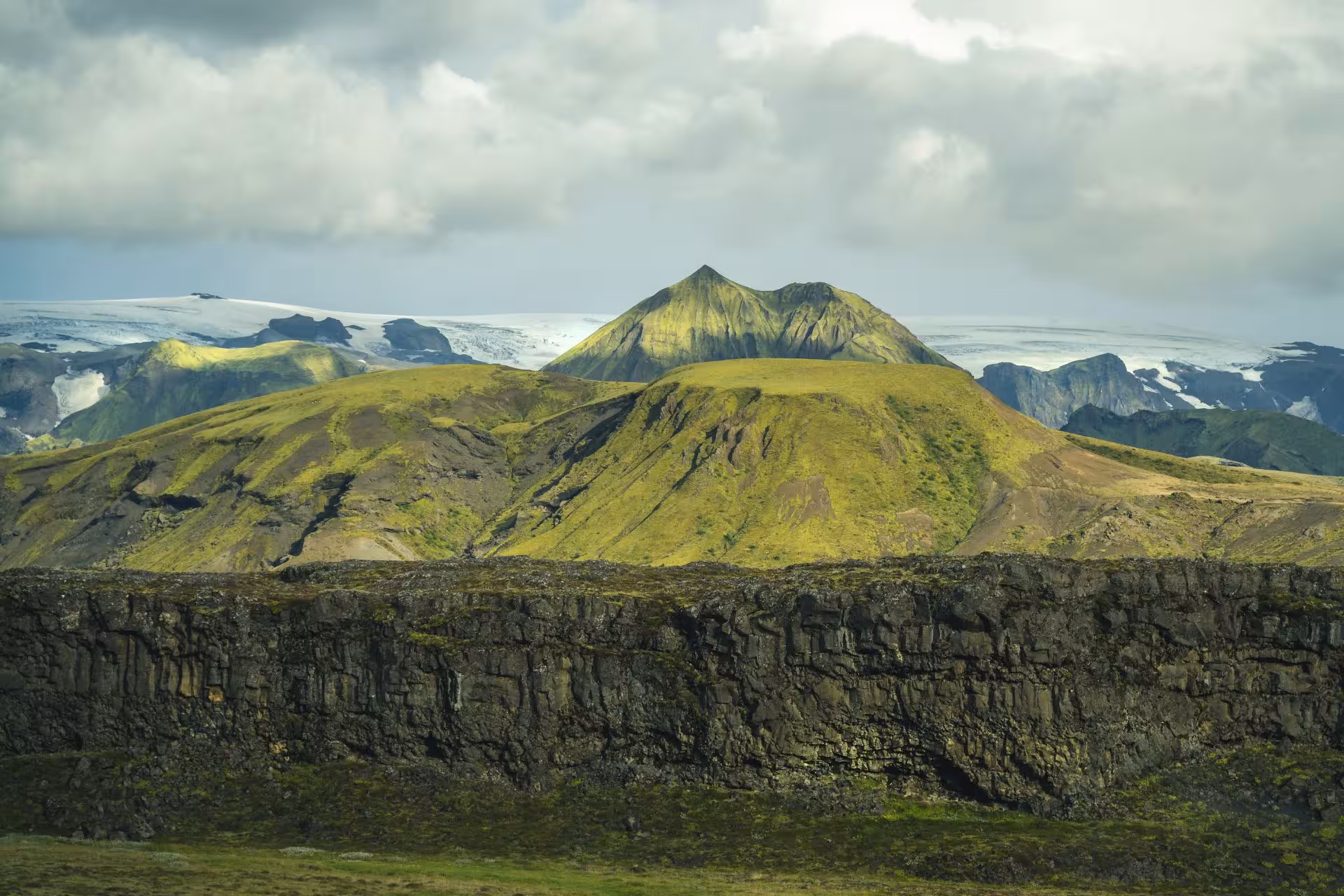 Moss-covered volcanic mountains with glacier in background, Thorsmork Highlands Iceland