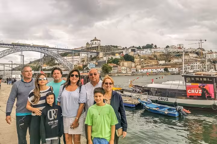 Group by Douro River boats in Porto with Dom Luís I Bridge, on Three Shrines Pilgrimage Fátima Santiago Nazaré