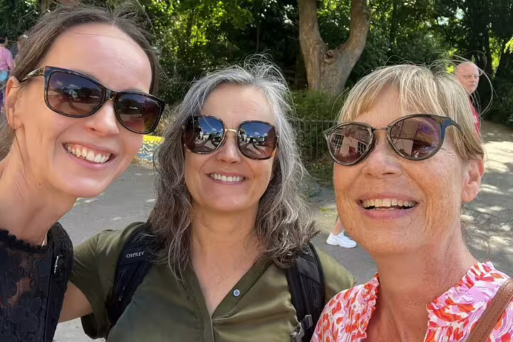 Three smiling women wearing sunglasses on a sunny outdoor walking tour in Copenhagen