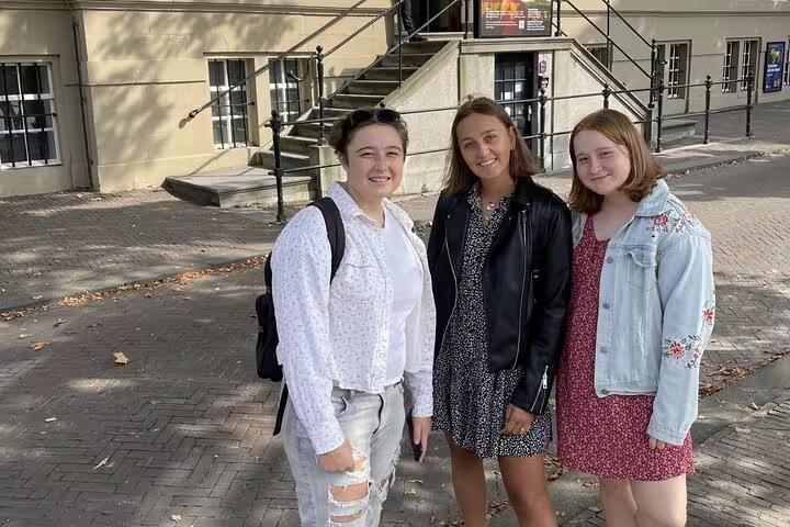 Three young women smiling together on a brick street in The Hague old town