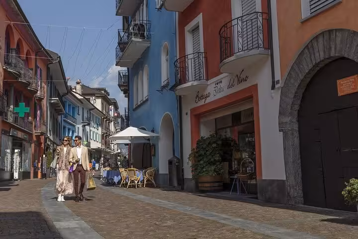 Charming street in Ticino lined with colorful buildings and outdoor cafes, perfect for a leisurely stroll.