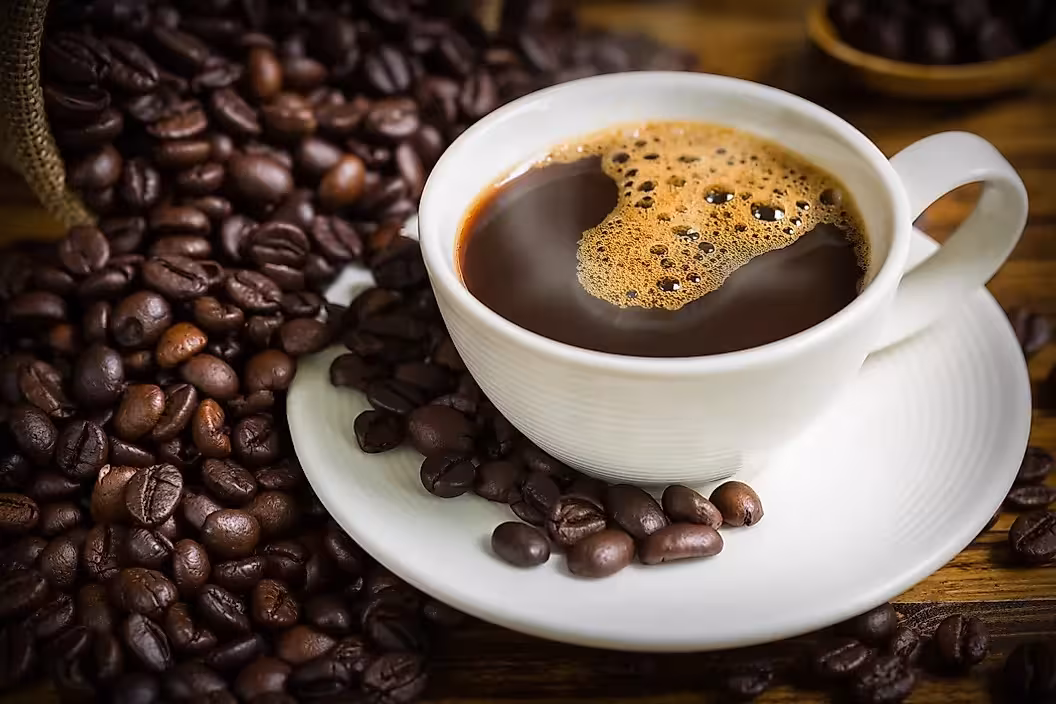 Freshly brewed coffee in a white cup surrounded by roasted beans, showcasing Tierra Amiga's artisanal organic blend.