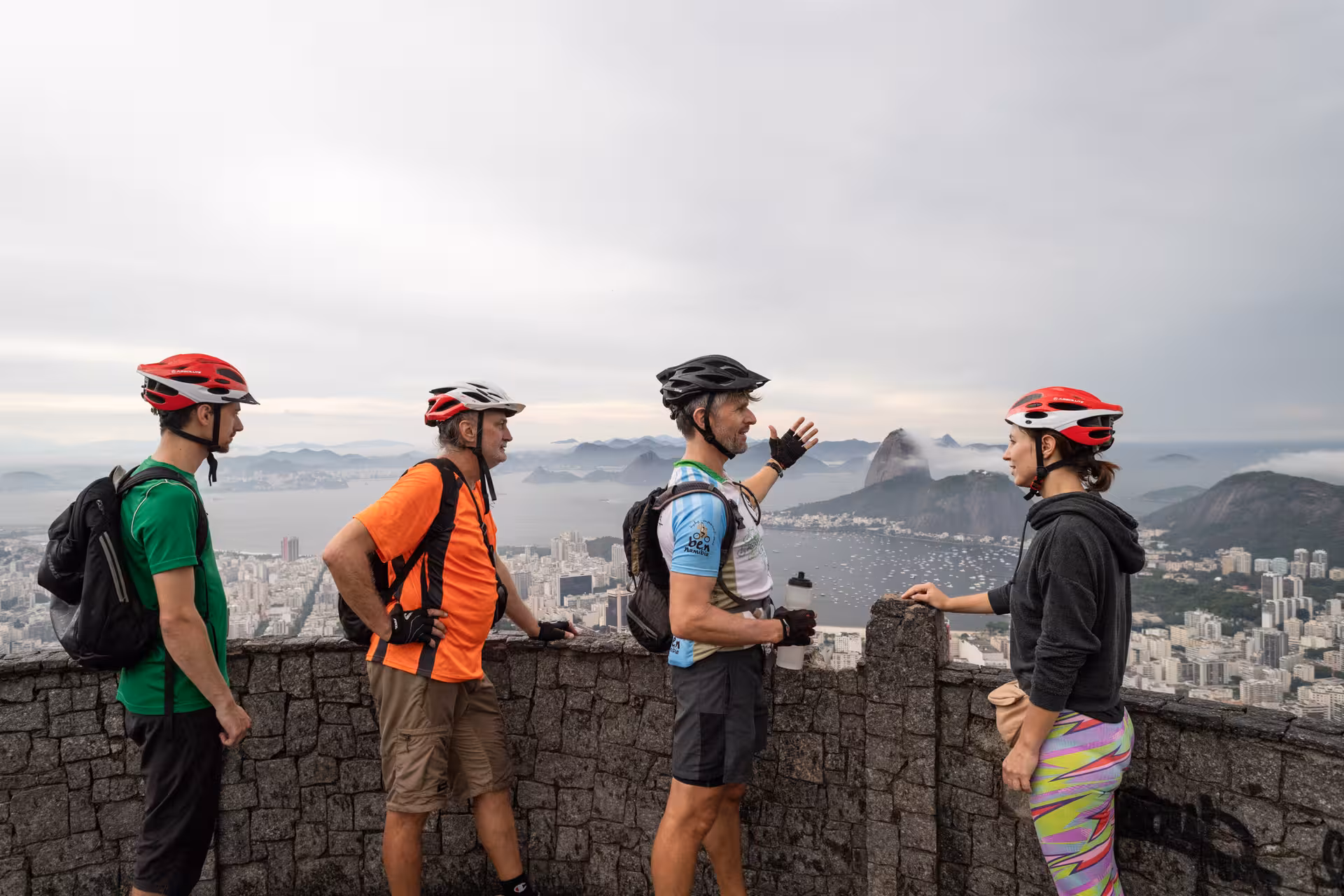 Mountain bikers at Rio de Janeiro lookout with Sugarloaf view during Tijuca Forest bike tour adventure
