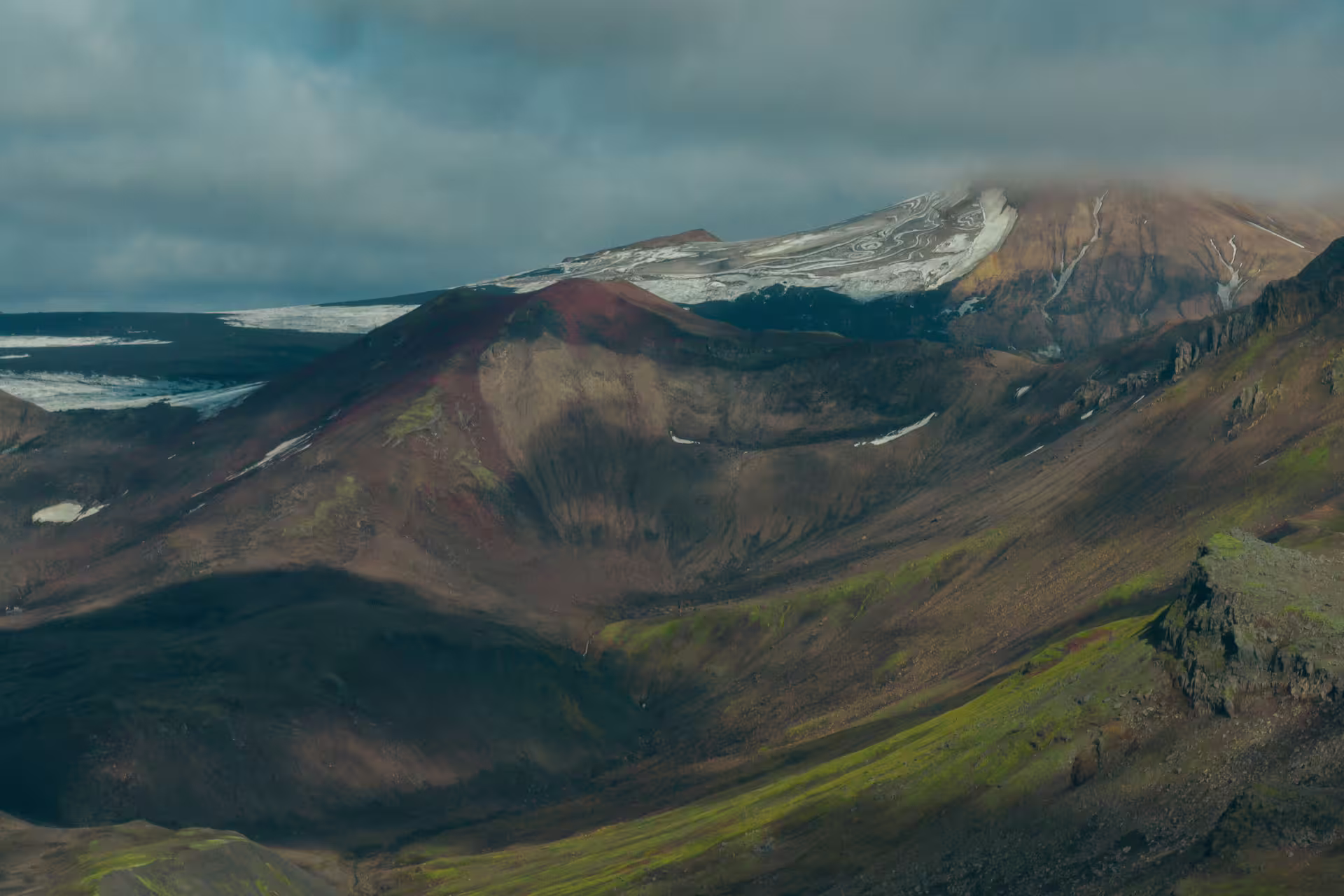 Dramatic volcanic landscape with glacier ice and green moss slopes on Tindfjallajokull Katla Geopark guided day trip