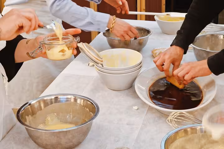 Participants preparing tiramisu with creamy layers and coffee-soaked biscuits during a cooking class in Rome.