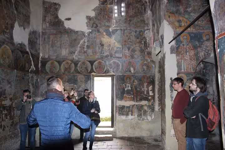 Tourists explore ancient frescoes in a historic church on the Tirana to Berat city tour.