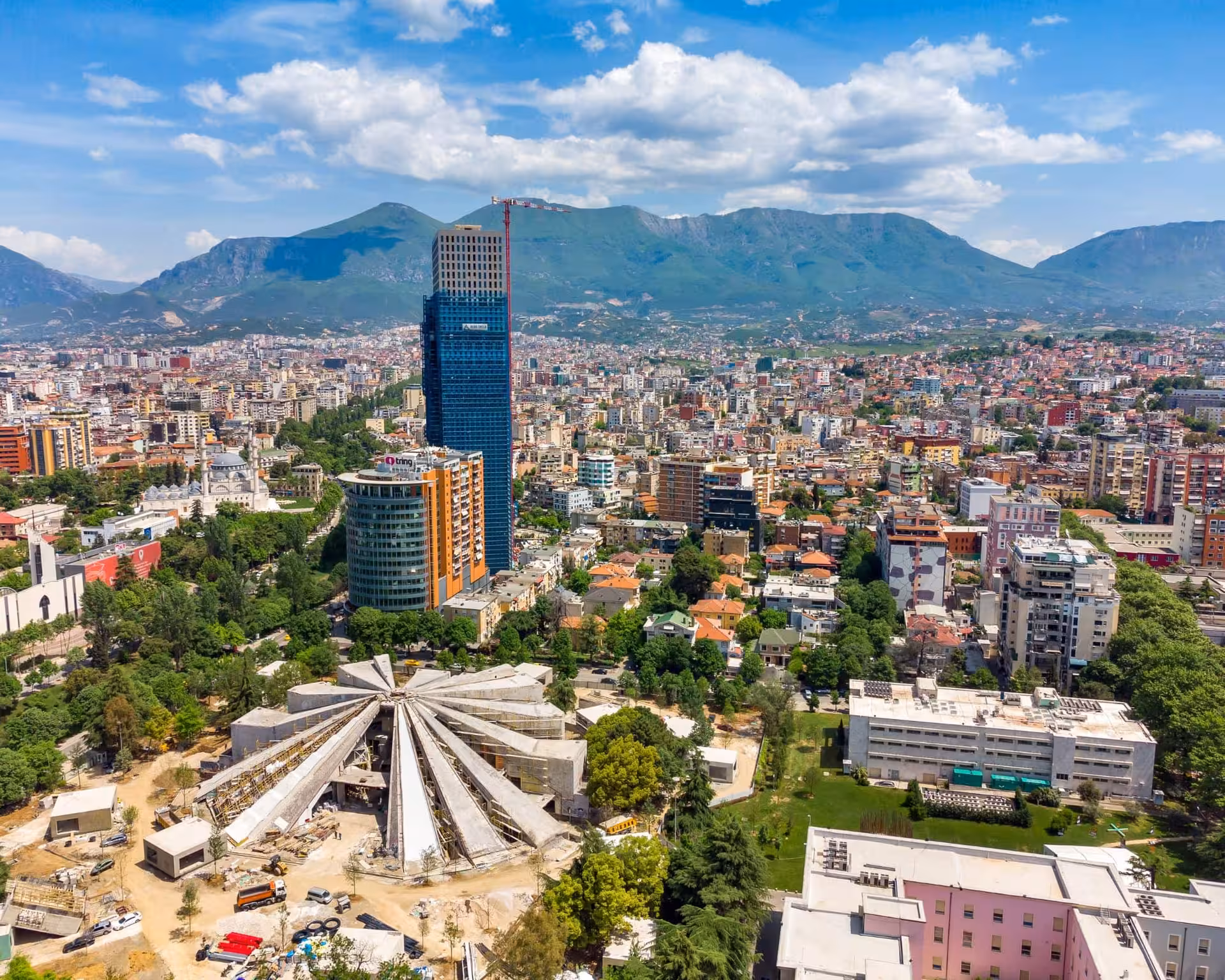 Aerial view of Tirana's skyline with mountains, showcasing Albania's vibrant capital on a clear day.