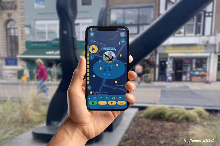 Hand holding smartphone with Titanic walking tour app map near Southampton city center anchor sculpture