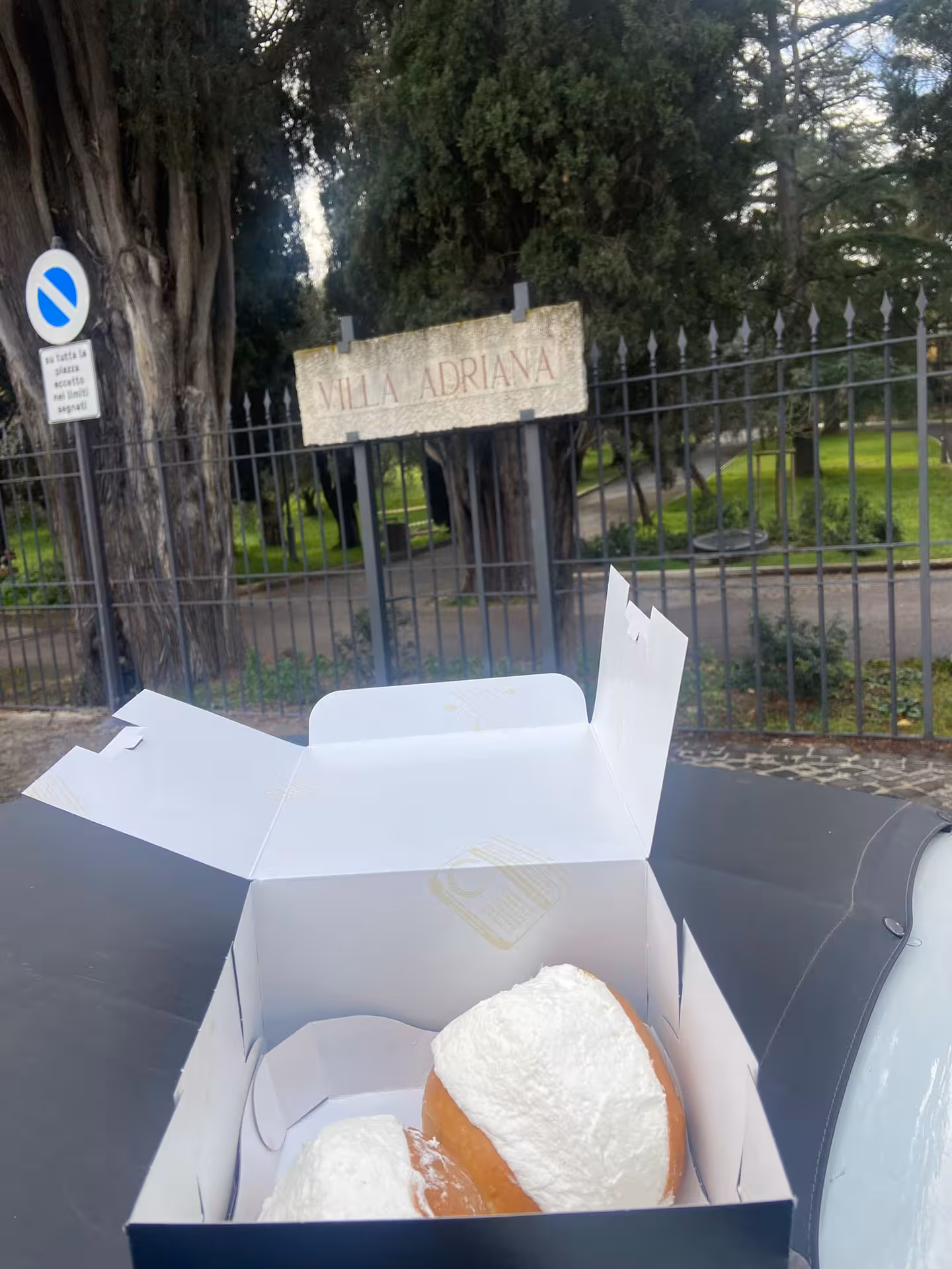 Delicious pastries in a box with Villa Adriana sign in the background, enhancing the Tivoli tour experience by Fiat 500.