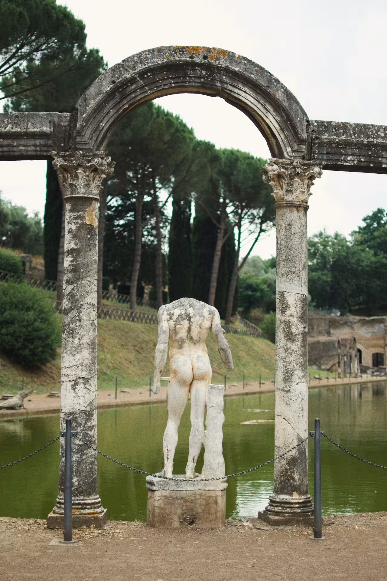 Ancient statue framed by stone arches at Hadrian's Villa during the Tivoli Vintage Tour by Fiat 500.