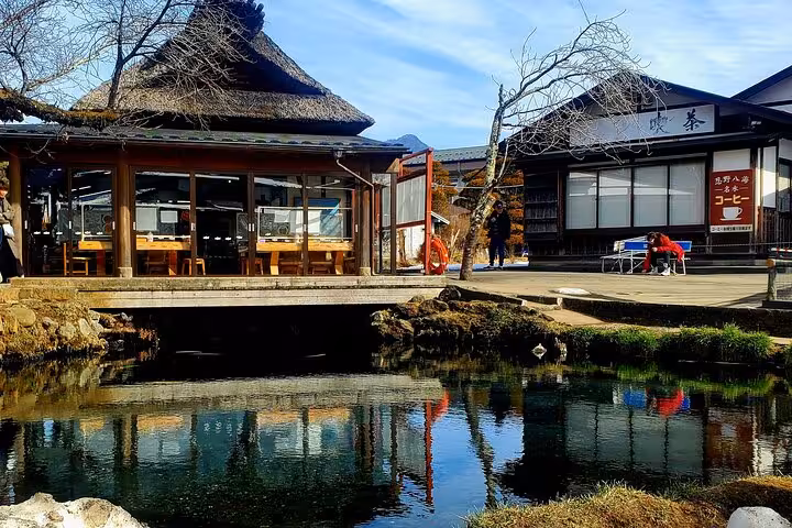 Traditional Japanese teahouse with thatched roof reflecting in a serene pond near Mt Fuji on a Tokyo Hakone guided tour