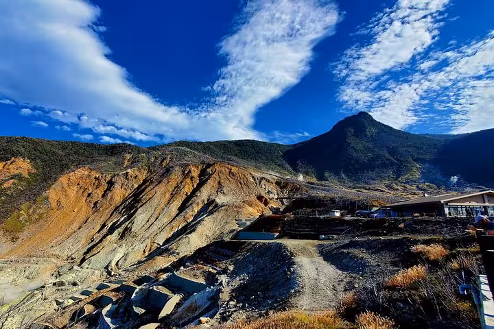 Dramatic landscape of Owakudani's volcanic terrain under blue skies, featured in the Tokyo to Hakone guided tour.