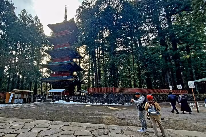 Tourists admire the iconic five-story pagoda surrounded by lush forest in Nikko on a Tokyo to Nikko private tour.