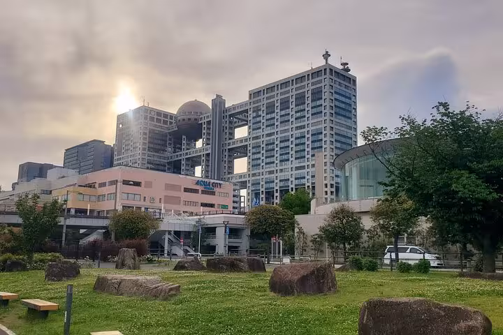 Sunset over Odaiba's futuristic architecture, highlighting Fuji TV building, ideal for a Tokyo private tour adventure.