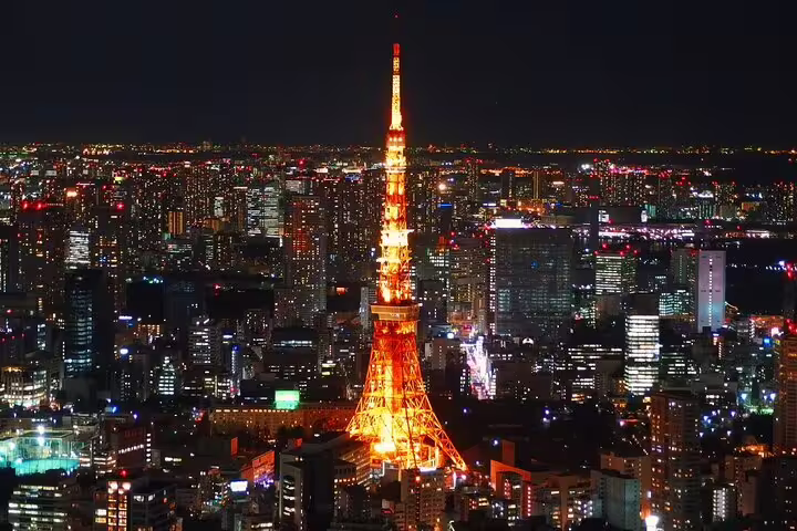 Tokyo Tower illuminated in orange at night with sprawling city lights of Tokyo skyline