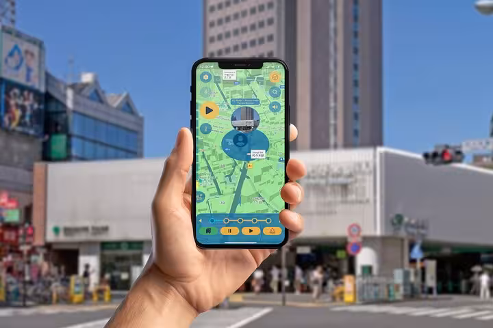 Hand holding phone with self-guided Tokyo walking tour app showing Meiji to Shibuya street navigation map