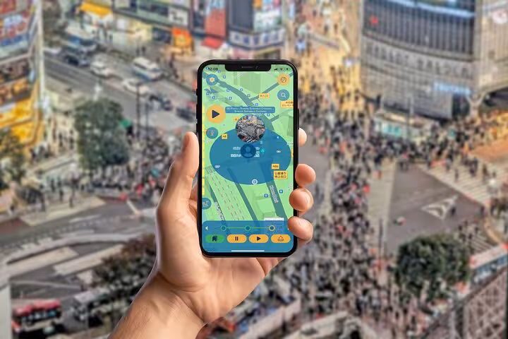 Hand holding smartphone with interactive Tokyo walking tour app displaying Shibuya Crossing map navigation guide
