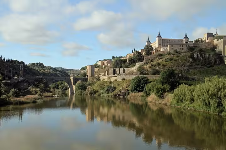 Scenic view of Toledo's Alcázar and river, highlighting natural beauty on a Granada, Toledo & Madrid excursion.