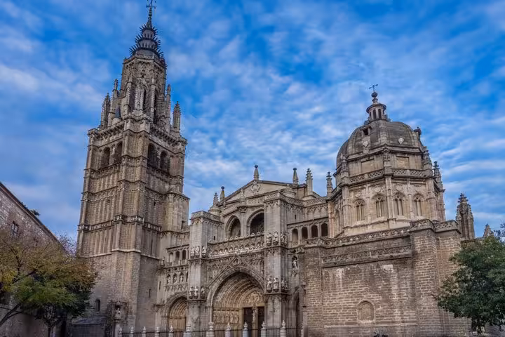 Gothic facade and bell tower of Toledo Cathedral against a blue sky, Spain
