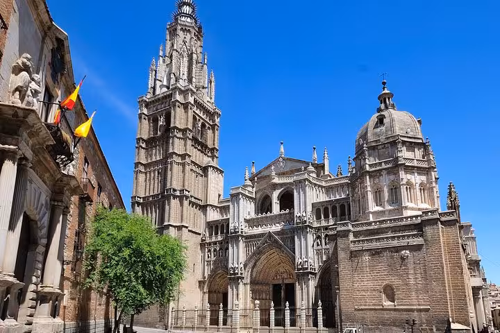 Impressive facade of the Toledo Cathedral under a clear blue sky, showcasing Gothic architecture on a day tour.