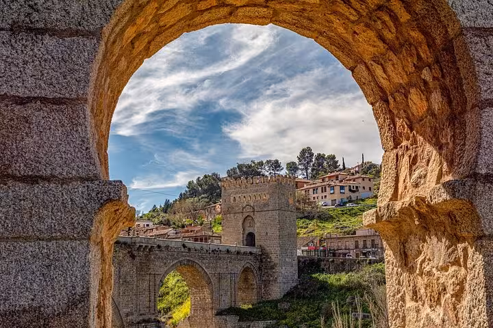 View through a stone archway of Toledo's historic bridge and skyline, ideal for a Granada, Toledo & Madrid tour.