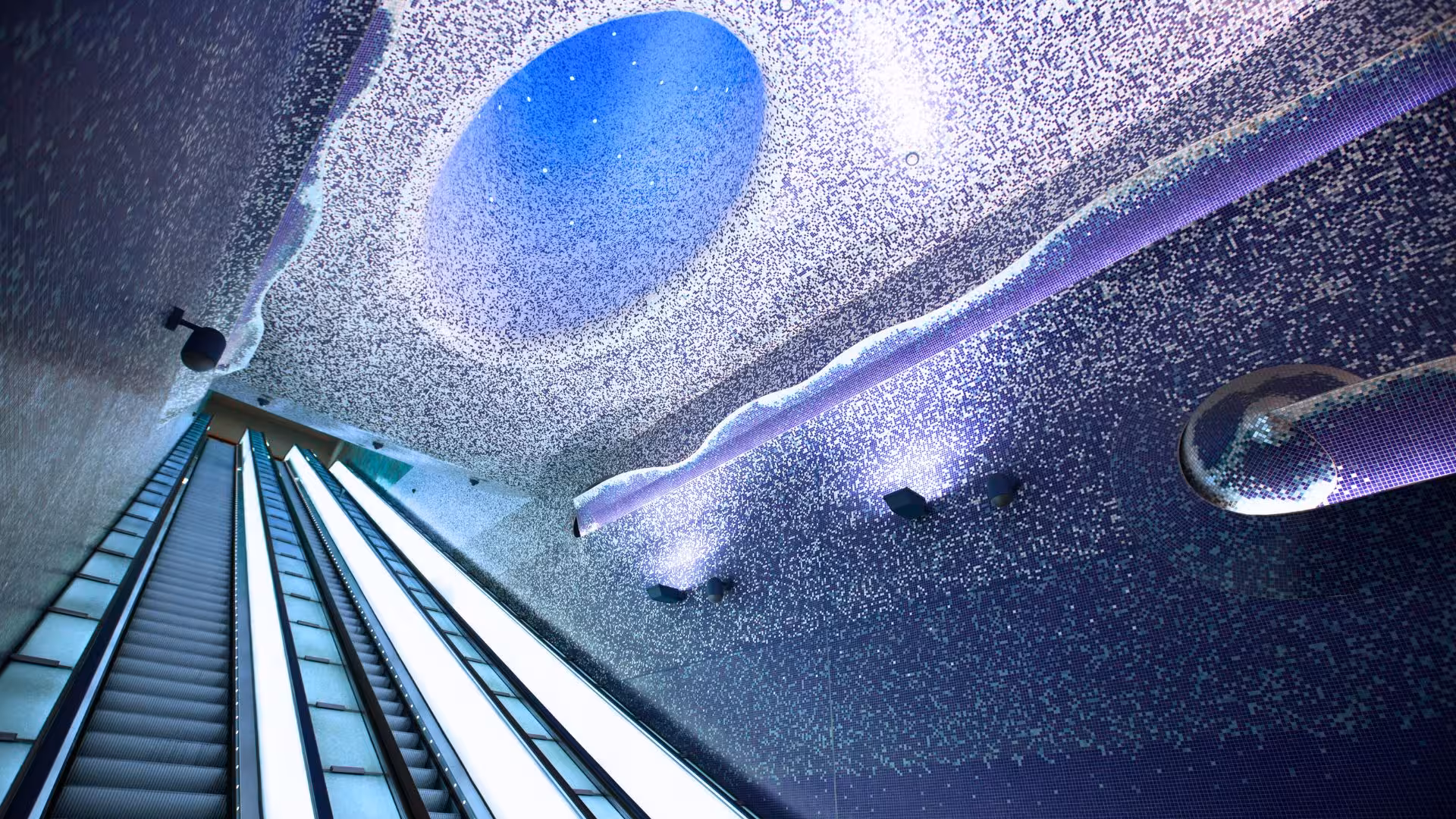 Modern escalator under a blue mosaic ceiling at Toledo Metro Station in Naples, showcasing artistic design.