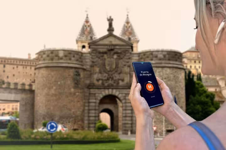 Tourist using audio guide app at Puerta de Bisagra gate in Toledo, Spain