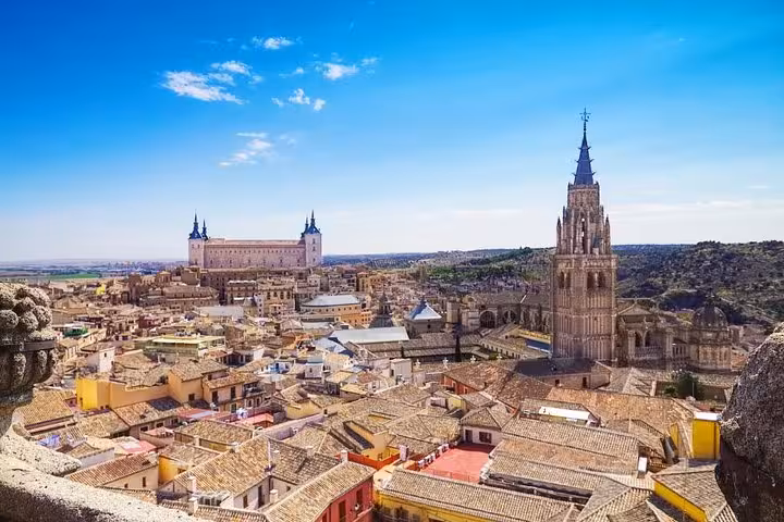 Panoramic view of Toledo's skyline featuring the iconic Cathedral and Alcázar under a clear blue sky.