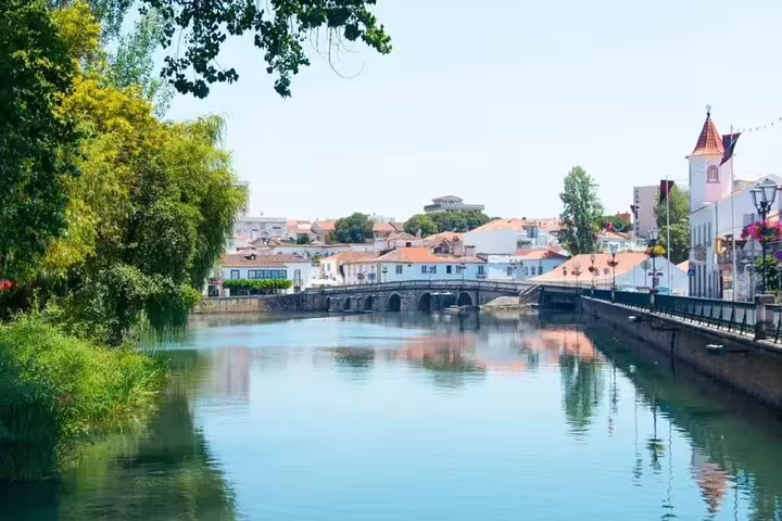 Scenic view of Tomar with a tranquil river and historic bridge, perfect for a private full day tour from Lisbon to Tomar & Coimbra.