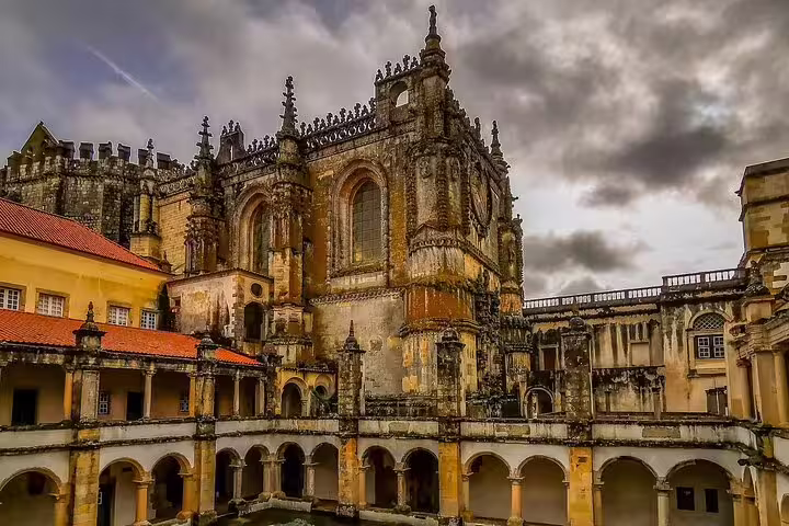 Gothic architecture of Tomar's Convent of Christ under cloudy skies, a highlight of Portugal's World Heritage Sites tour near Lisbon.
