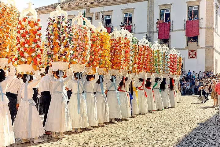 Colorful traditional procession in Tomar with participants carrying decorated flower trays, showcasing cultural heritage.