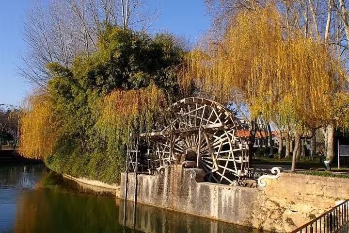 Scenic view of Tomar's traditional waterwheel by a serene river, showcasing the town's medieval charm.