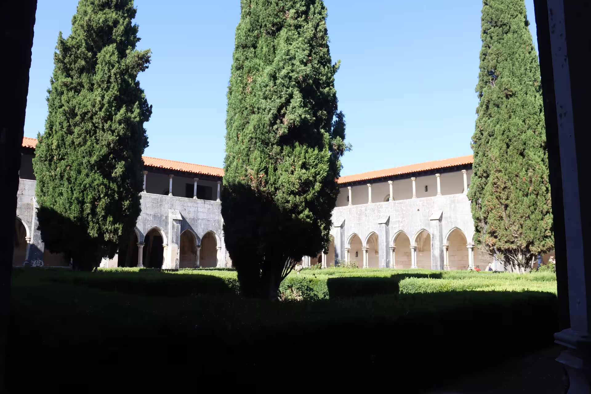 Serene courtyard of a historic monastery in Tomar, featuring tall cypress trees and medieval arches, ideal for private tours.