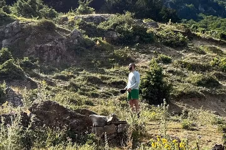 Solo hiker enjoying the serene landscape of rocky terrain and greenery during the Tomor Mountain Lakes adventure tour.