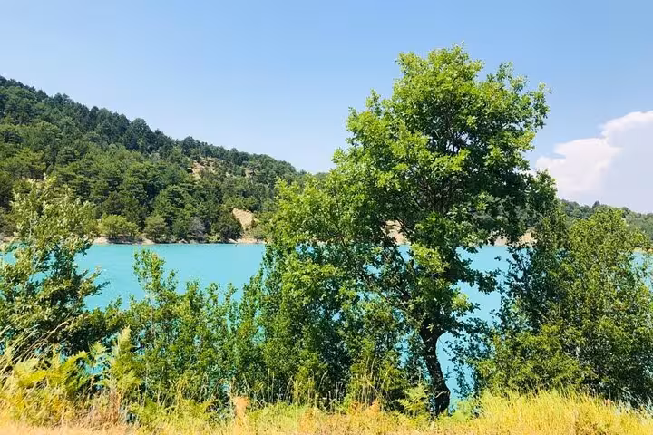 Vibrant turquoise lake surrounded by dense forest, perfect for swimming on the Tomor Mountain Lakes tour.