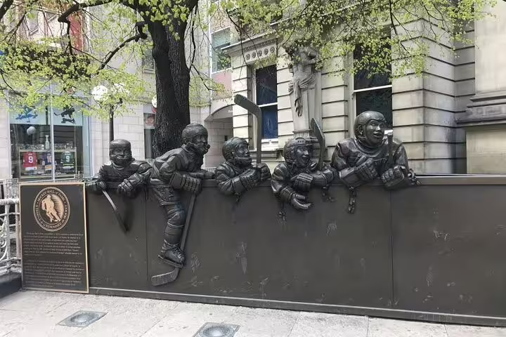 Bronze sculpture of hockey players peering over boards on Toronto's historic Old Town street