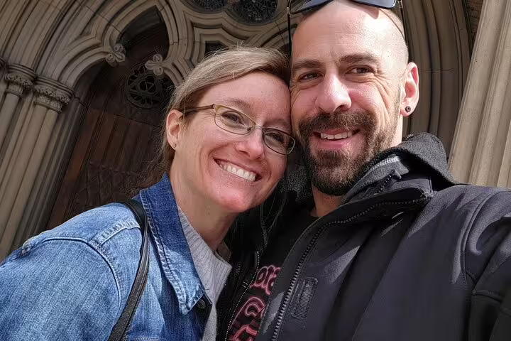 Smiling couple taking a selfie in front of a historic stone building in Toronto's Old Town