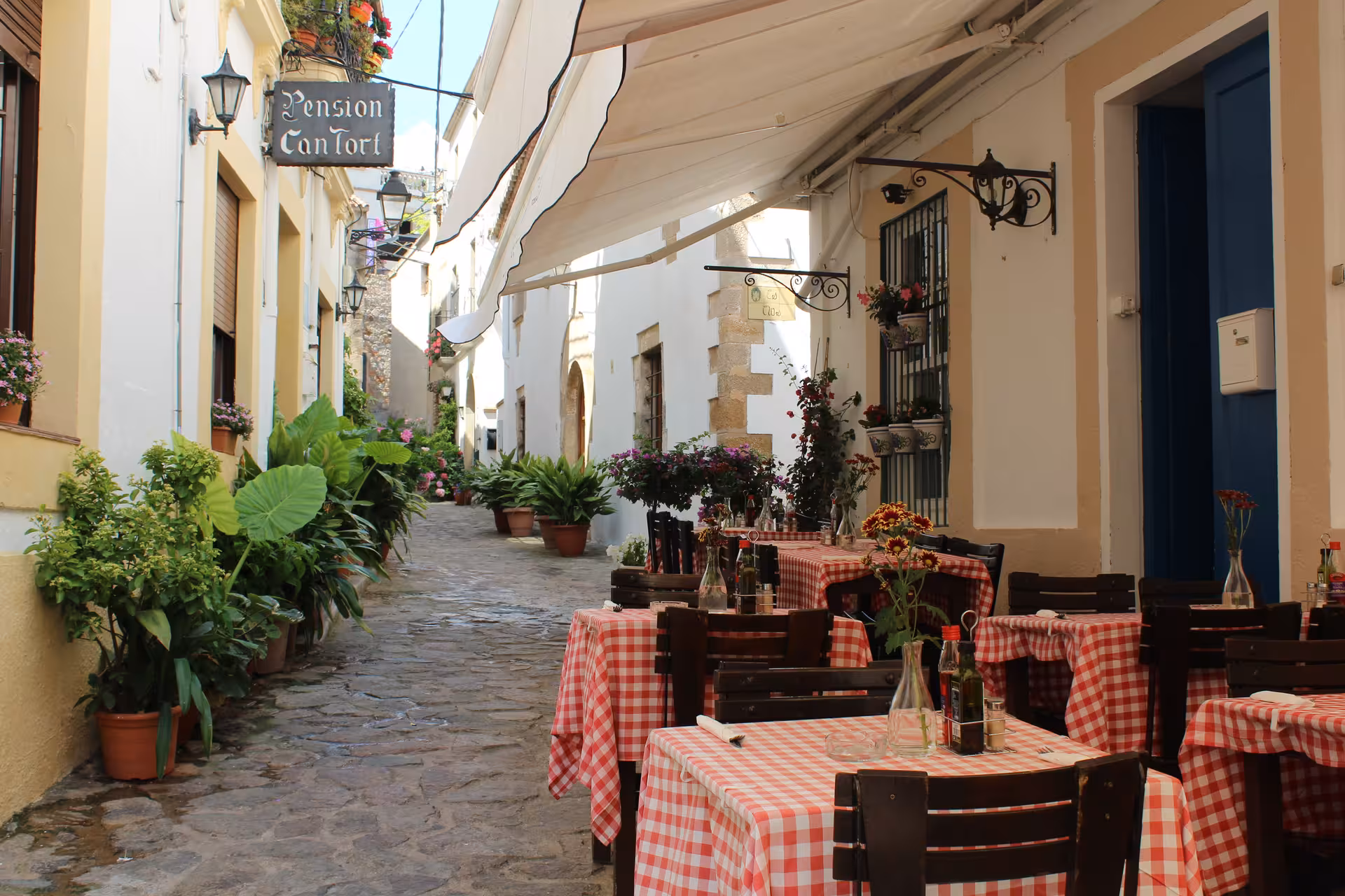 Charming Tossa de Mar old town street with café terraces, a highlight of Costa Brava day trip from Barcelona