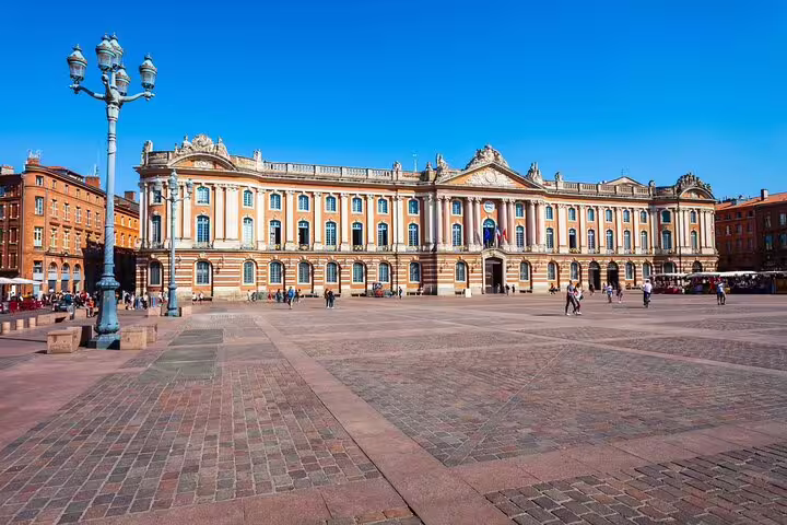 Place du Capitole square with the ornate pink brick Capitole de Toulouse building on a sunny day