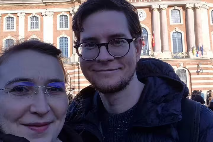 Couple smiling in selfie in front of Toulouse Capitole building during guided walking tour