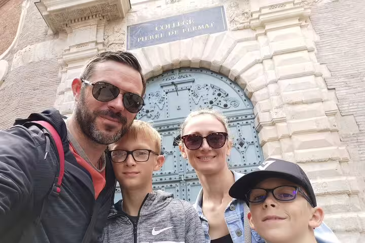 Family selfie in front of Collège Pierre de Fermat historic entrance in Toulouse
