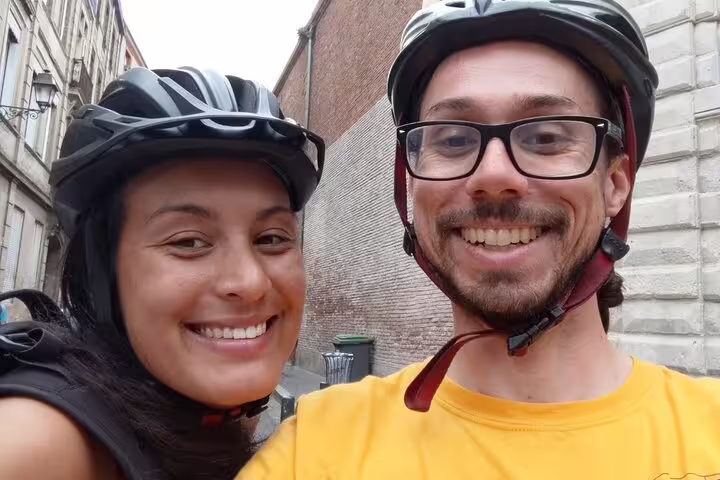 Two smiling tourists wearing bicycle helmets on a guided city tour in Toulouse